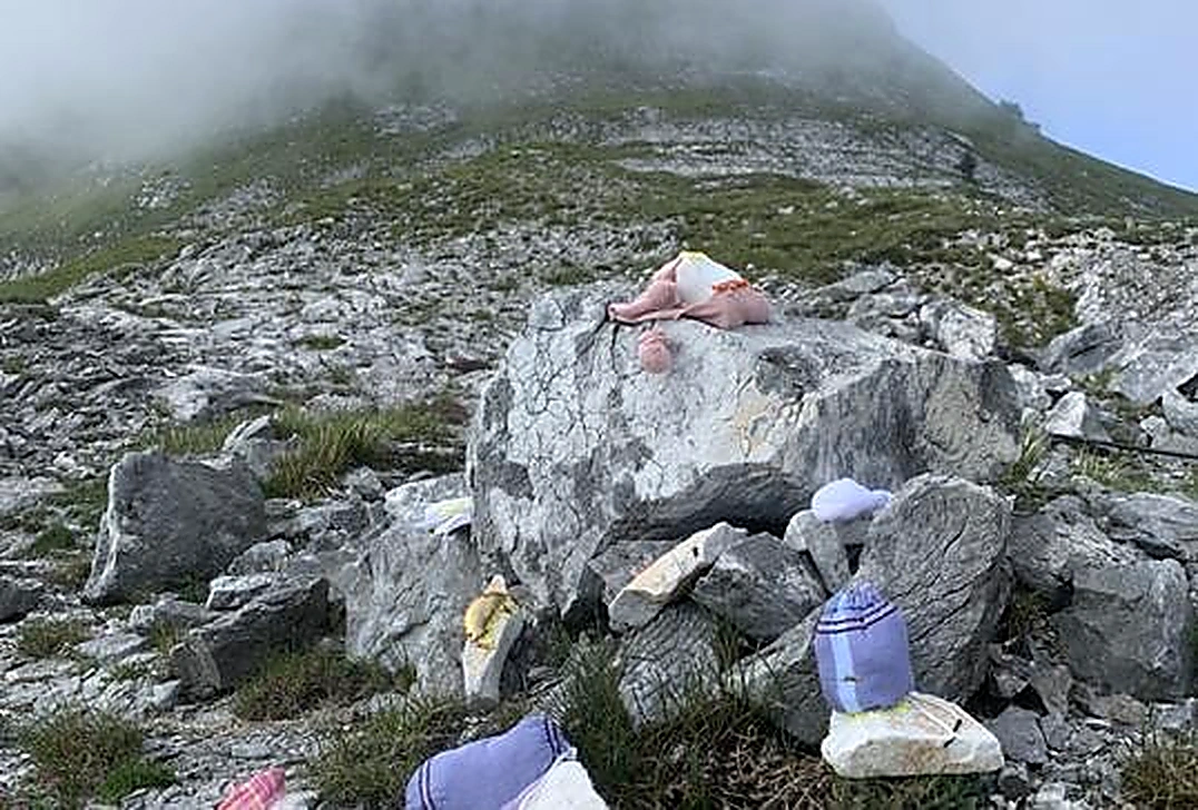 山坡碎石之间放置的粉色织物与缝制物件